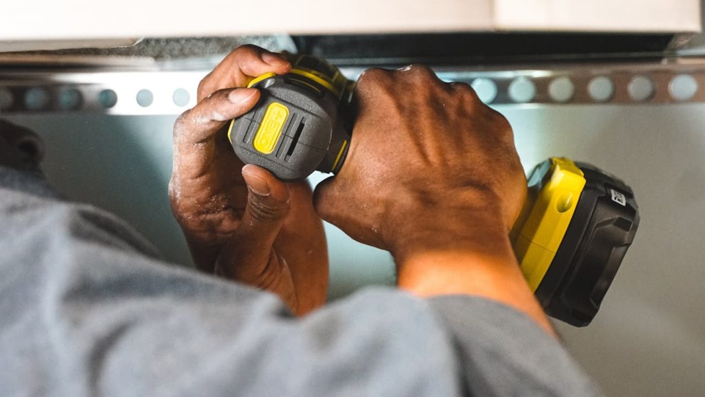 Close-up of workers hands operating a power tool during a construction task.